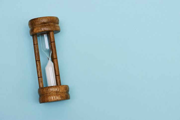 Sand running through the bulbs of an hourglass measuring the passing time in a countdown to a deadline with copy space