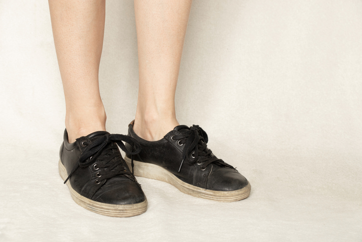 Black sneakers on the feet of a girl on a white carpet, shoes