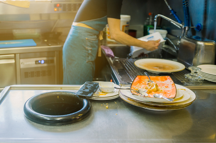 Unrecognizable man washing dishes at kitchen