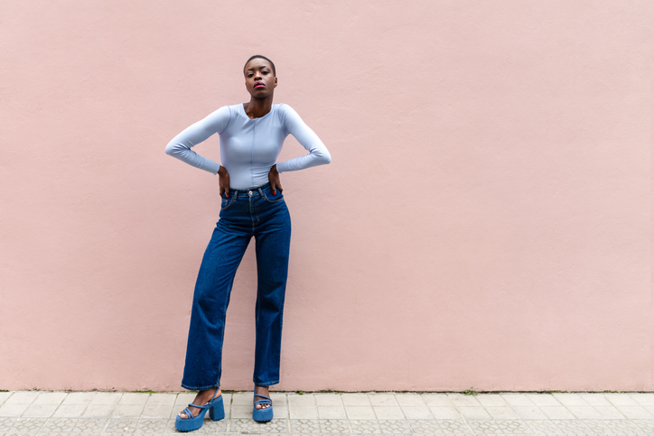 A female person smiling, with a pink wall in the background