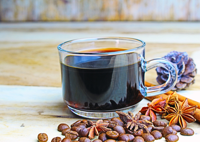 cup of coffie with cinnamon and star anise on wooden background