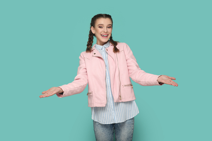 Friendly teenager girl standing with open hands, sharing with somebody for free.
