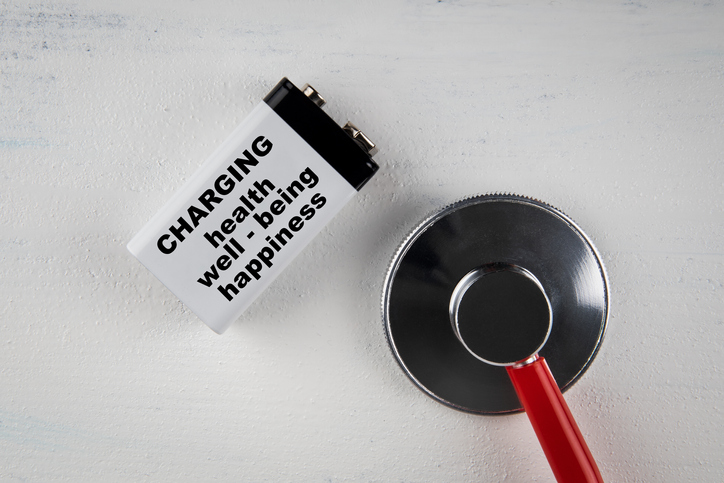Helth, Well being and happiness concept. Battery and doctor's stethoscope on a white wooden background
