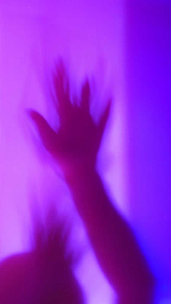 Defocused abstact silhouette of arm, hand spooky action, alien, ghost, Halloween concept, haunted and horror in multicolor background