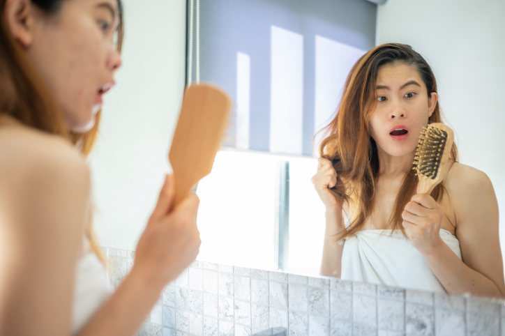 Asian woman having shock emotion after her hair fall while brushing.