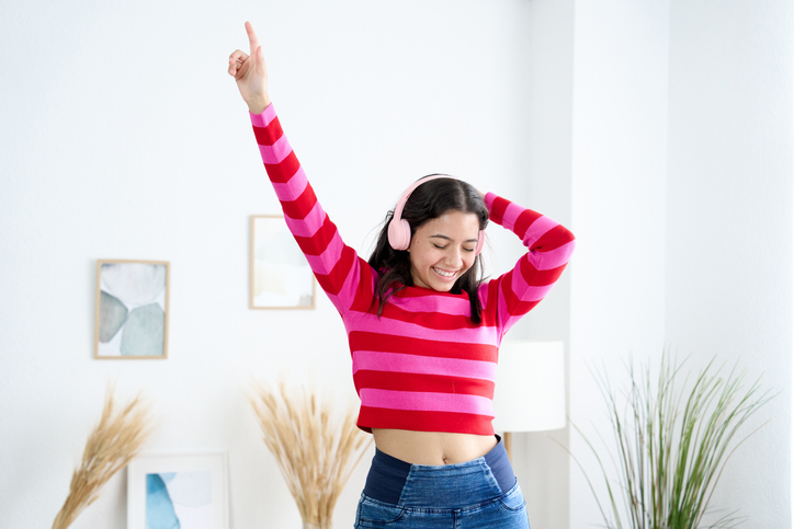 happy young woman listening to music with headphones and dancing