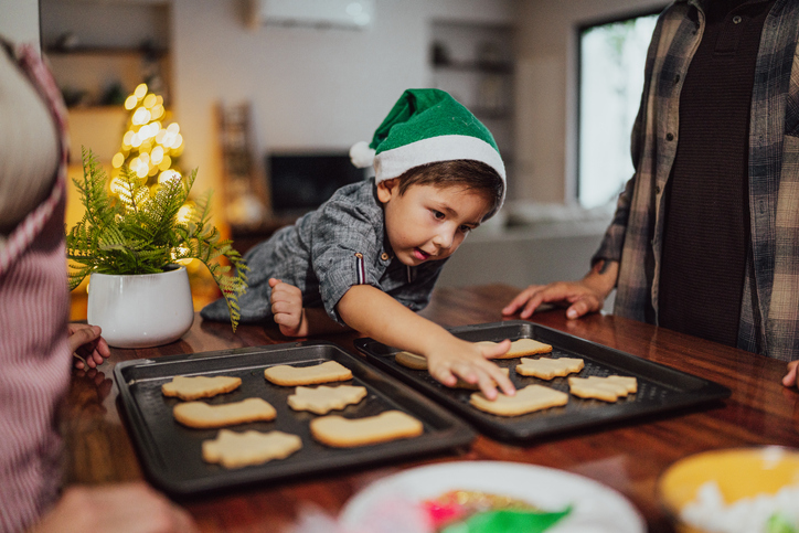 Child boy preparing christmas cookies and talking in kitchen at home