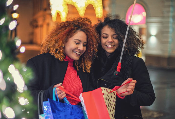 Young beautiful girls having fun while shopping presents for the Christmas