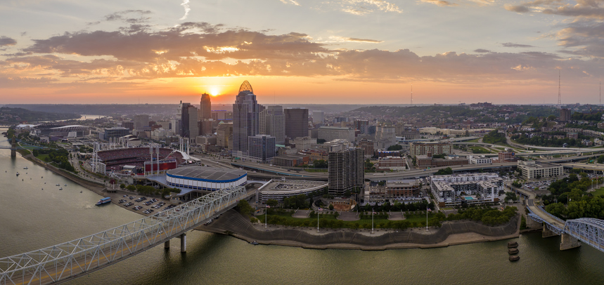Aerial view of downtown district highway traffic in Cincinnati city, Ohio at sunset. Brightly illuminated high skyscraper buildings in modern American midtown