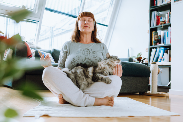 portrait of middle aged woman meditating, yoga at home