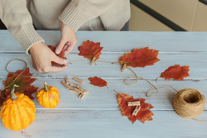 Homemade garland of colored autumn leaves with womans hands