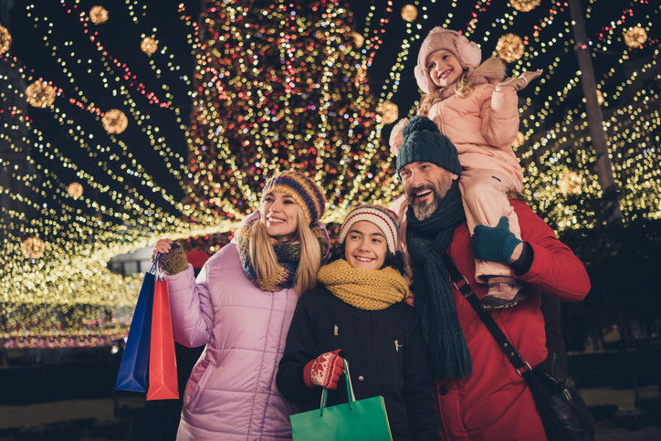 Photo of positive husband wife school children walking choosing xmas gifts riding shoulders outdoors city fair