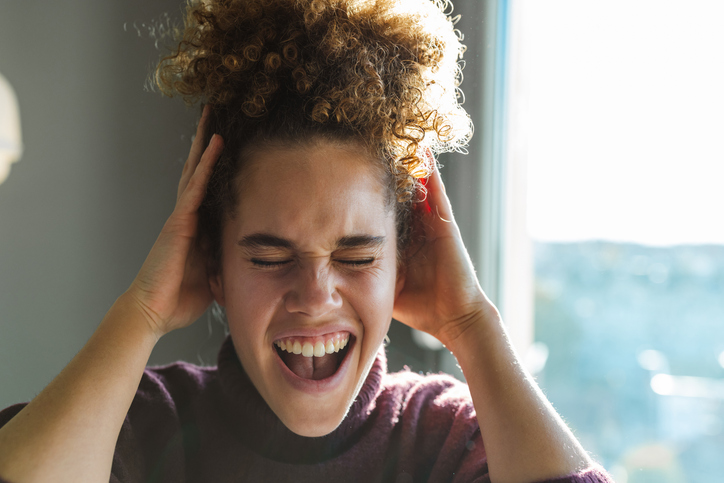 Joyful young woman laughing by the window in natural light