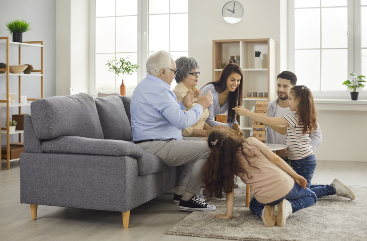 Happy mother, father, grandmother, grandfather and children playing board game at home