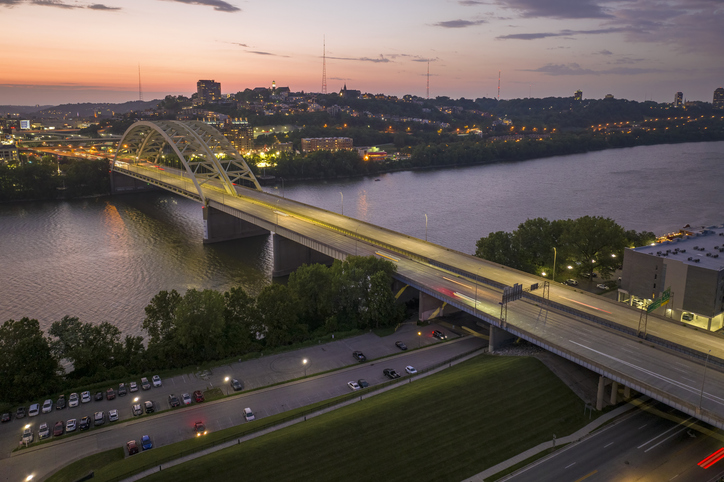 Highway traffic in Cincinnati, Ohio on Daniel Carter Beard Bridge with brightly illuminated high skyscraper buildings in downtown district. American city with business financial district at night