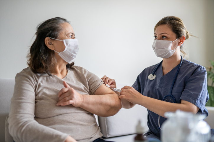 Senior woman gettin a COVID-19 vaccine at home