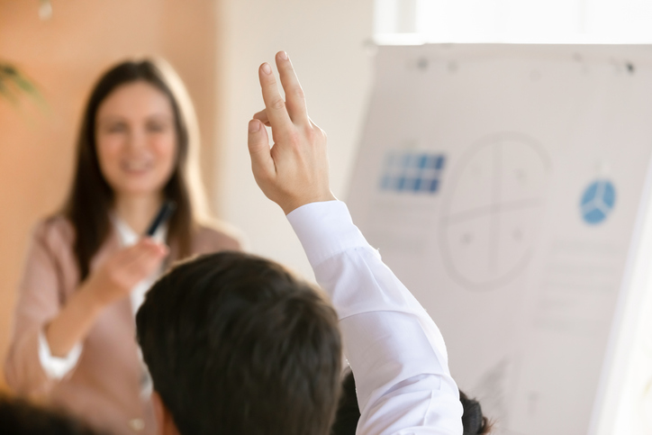 Business seminar student asking question to young female coach