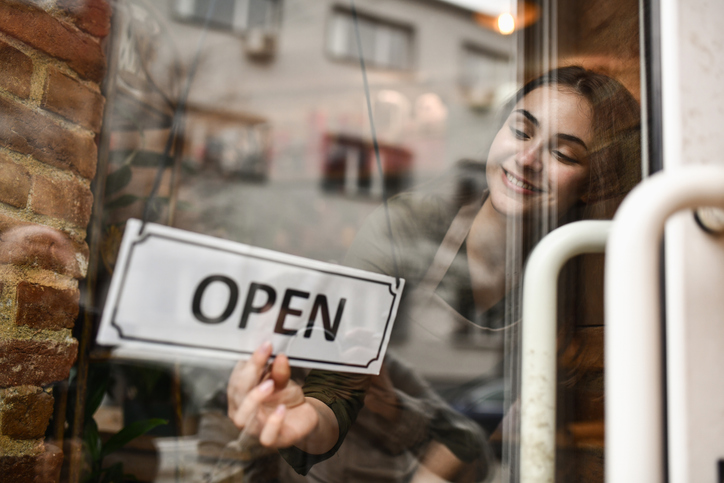 Smiling Business Owner Opening Store by Displaying Open Sign on Door