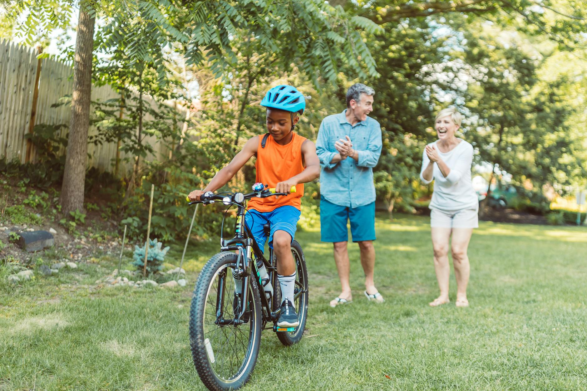 a happy couple cheering for their son riding a bike