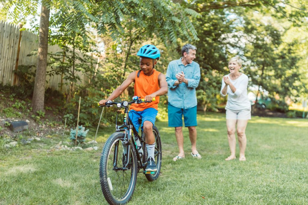 a happy couple cheering for their son riding a bike