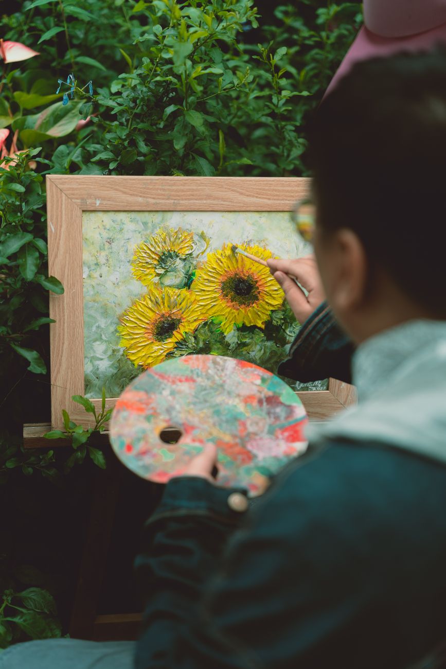 a man painting a sunflower on a canvas