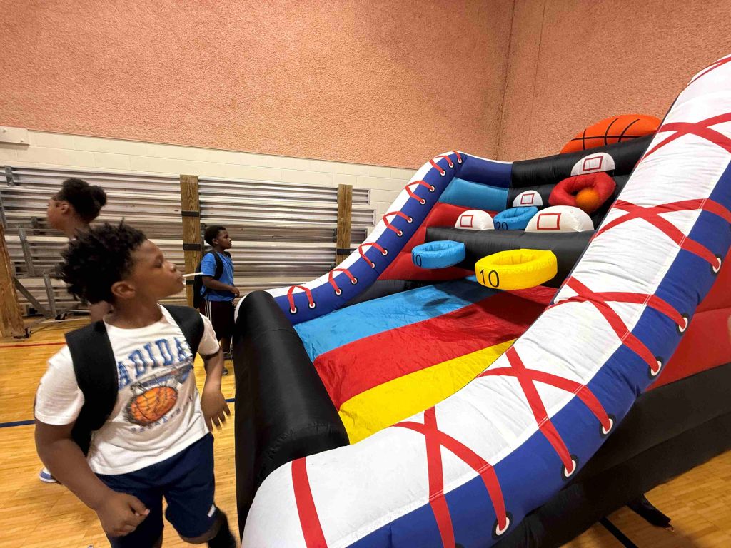 A group of children playing on an inflatable basketball court with colorful patterns and shapes.