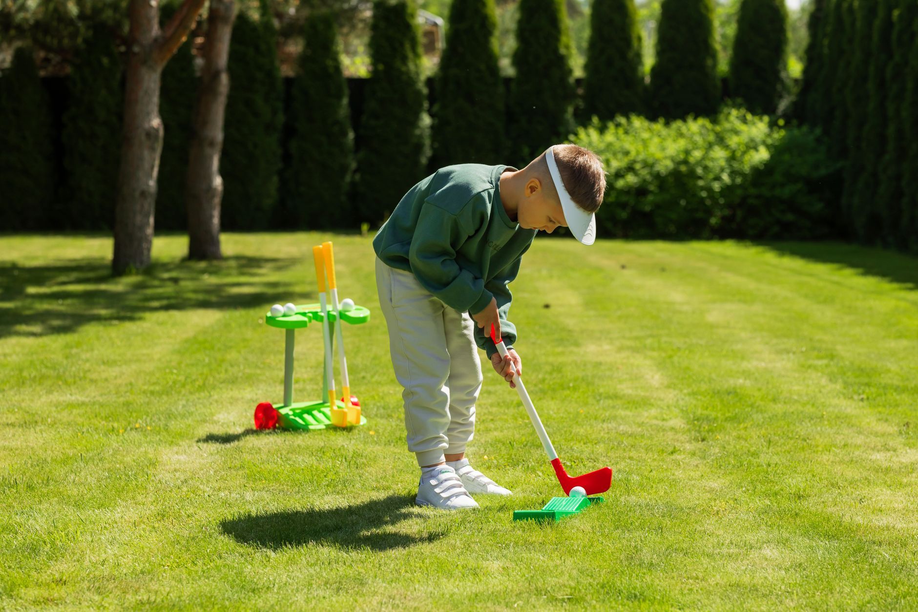 child playing mini golf outdoors in summer
